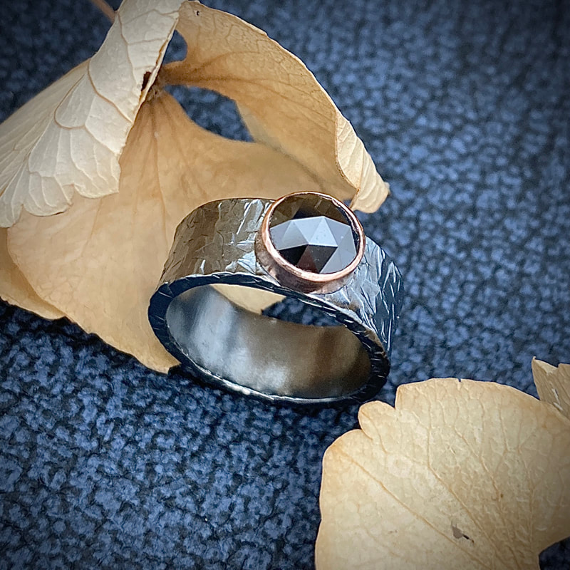 Ice textured silver band, with large black diamond set in a rose gold collet